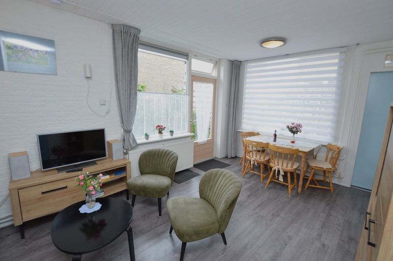 Bright dining and living room in vacation home Plevierstraat 18, De Koog, Texel with dining table and television.