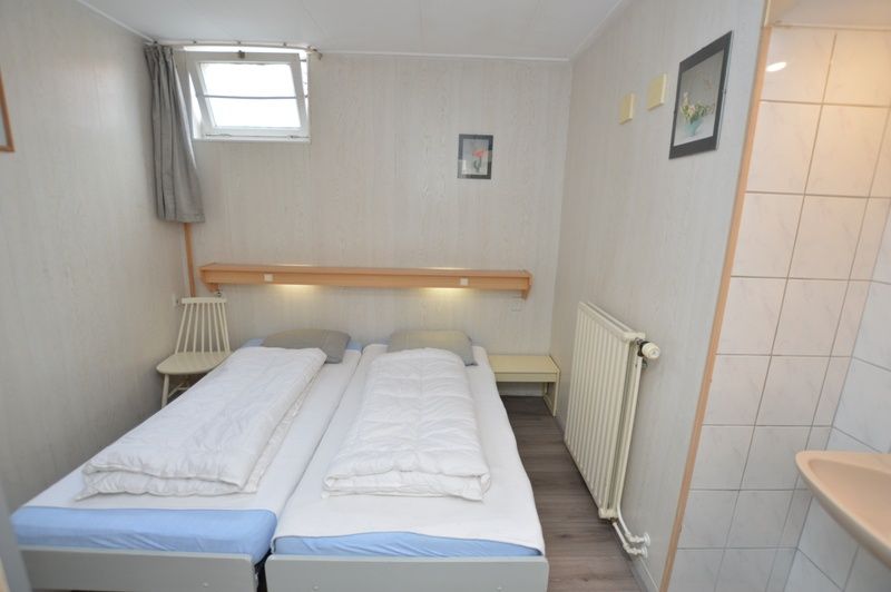 Second bedroom in Plevierstraat 18 vacation home, De Koog, Texel with two single beds and sink.