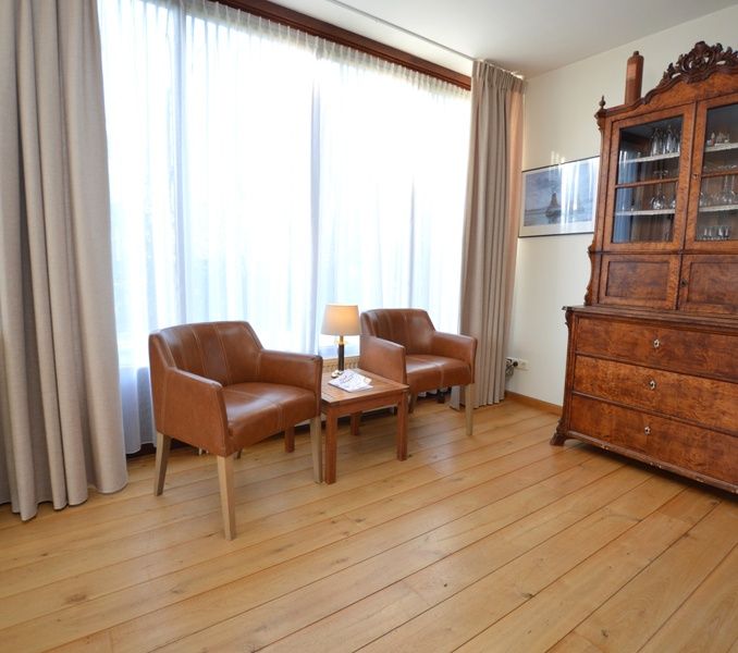 Stylish sitting area in Orchismient 35 vacation home, De Koog Texel, with antique cabinet.