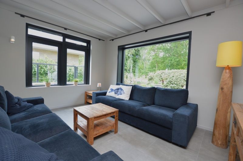 Gemuetliches Wohnzimmer in der Ruijslaan 73, De Koog, Texel, mit bequemen Sofas und grossen Fenstern.