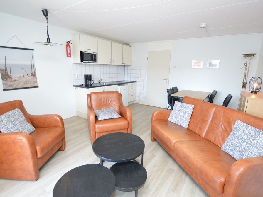 Gemuetliche Sitzecke im Motel Texel - Apartment 208/1L, De Koog, Texel, mit bequemen Ledersofas und einer offenen Kueche.