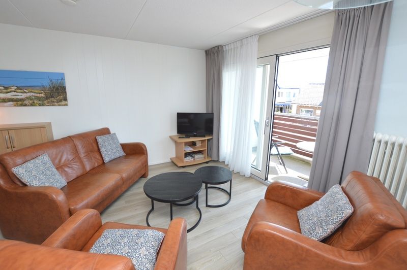 Geraeumiger Innenbereich des Motel Texel - Apartment 208/1L, De Koog, Texel, mit Zugang zu einem Balkon und einem Flachbildfernseher.