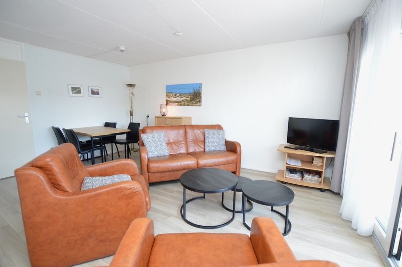 Attraktiv eingerichtetes Wohnzimmer im Motel Texel - Apartment 208/1L, De Koog, Texel, mit Ledersitz und Essecke.