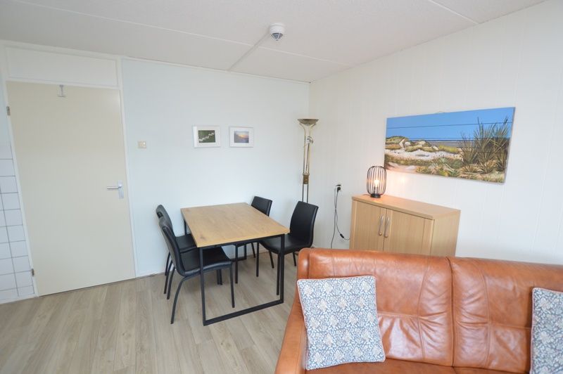 Essecke im Motel Texel - Apartment 208/1L, De Koog, Texel, mit Holztisch und stilvollen Stuehlen.