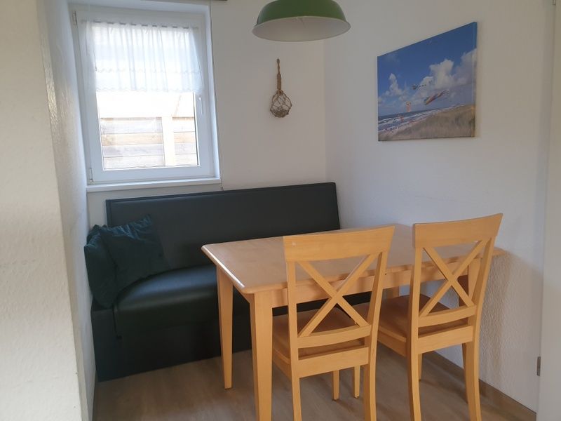 Dining area in De Duinpan - Duinhuisje Texel, De Koog, with wooden table and cozy sofa for family meals.