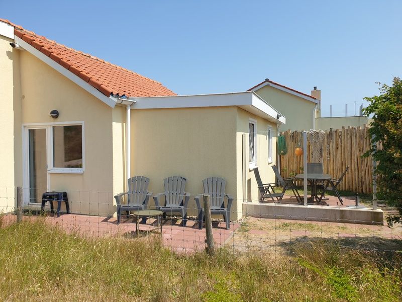 Spacious terrace at De Duinpan - Duinhuisje Texel, De Koog, with comfortable chairs and surrounded by nature.