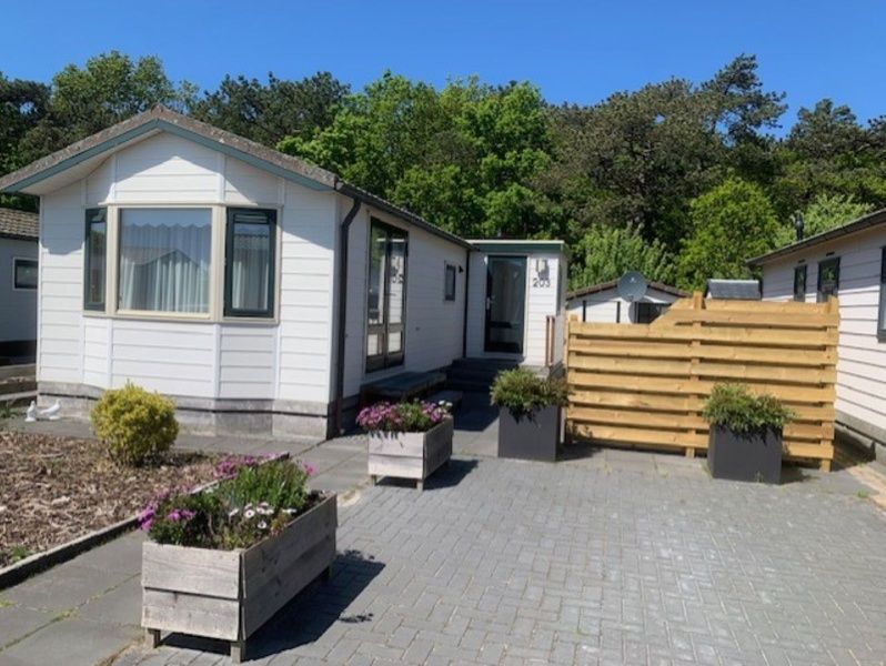 Vacation home Chalet Bregkoog 203, located in De Koog, Texel, with spacious driveway and green surroundings.