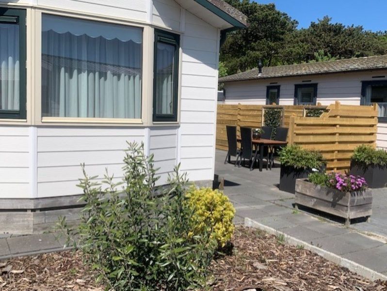 Terrace Chalet Bregkoog 203 on Texel, De Koog with cozy seating area and green plants.