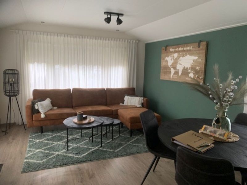 Stylish living room Chalet Bregkoog 203 in De Koog, Texel with comfortable sofa and world map decoration.