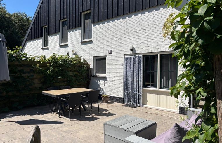 Enjoy the sunny patio at Cottage in De Koog, Texel, with comfortable outdoor furniture and green surroundings.