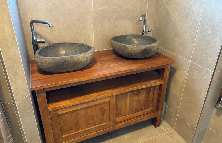 Stylish bathroom with double sink in cottage in De Koog, Texel, fitted with natural stone washbasins.