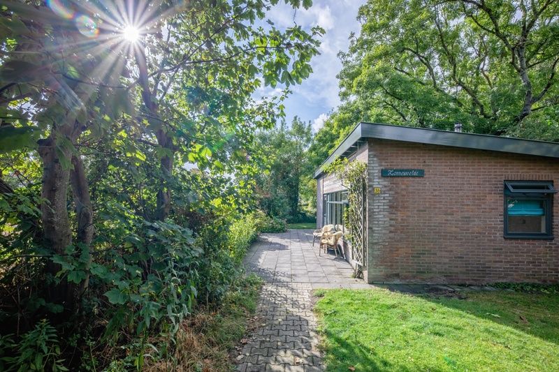 Veranda des Ferienhauses De Zonneweelde in De Koog, Texel, mit gruener Umgebung und Sitzgelegenheiten.