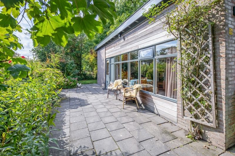 Terrasse von De Zonneweelde in De Koog, Texel, mit Blick auf den Garten und bequemen Stuehlen.