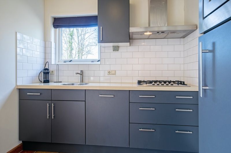 Kuechenbereich des Ferienhauses De Zonneweelde in De Koog, Texel, mit weissen Fliesen und Gasherd.