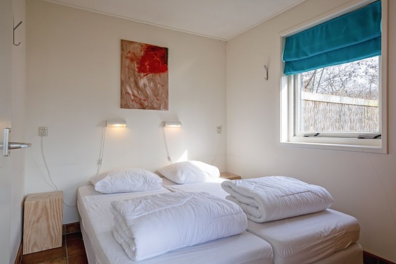 Schlafzimmer des Ferienhauses De Zonneweelde in De Koog, Texel, mit Doppelbett und Kunst an der Wand.