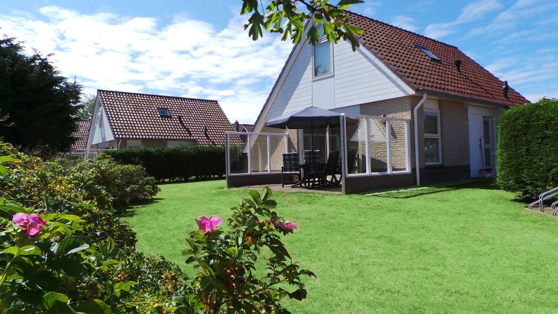 Enjoy the green garden and terrace of Villa 5, De Koog, Texel, perfect for relaxing outdoor activities.