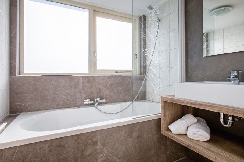Modern bathroom in Villa 5, De Koog, Texel, with a spacious bathtub and natural light for ultimate comfort.
