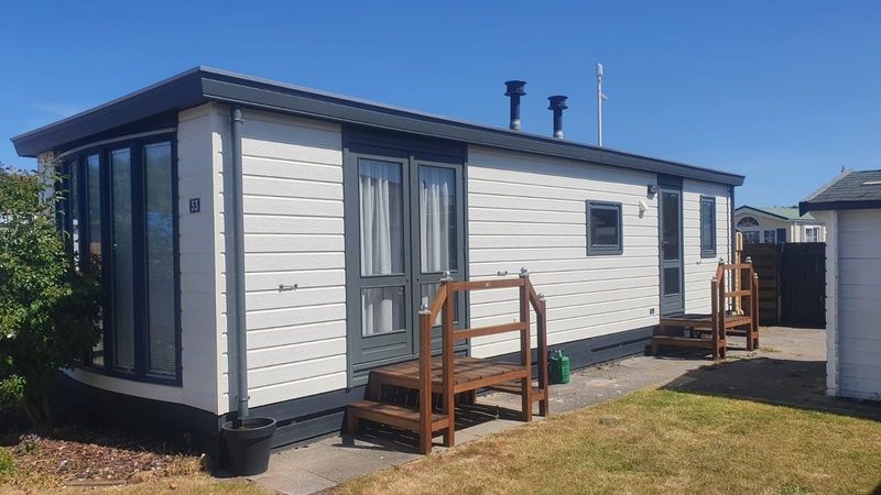 Sunny exterior of Chalet Bregkoog 33, Chaletpark Bregkoog, De Koog, Texel, with an inviting terrace and wooden steps.