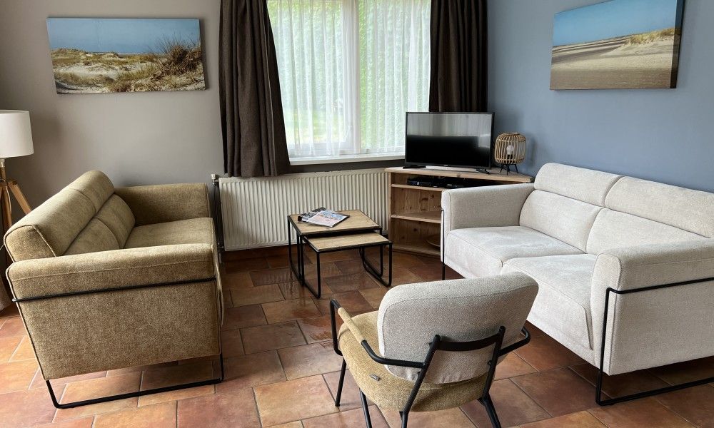 Cozy living room of Koetshuis vacation home in De Koog, Texel, with comfortable sofas and a television for relaxation.