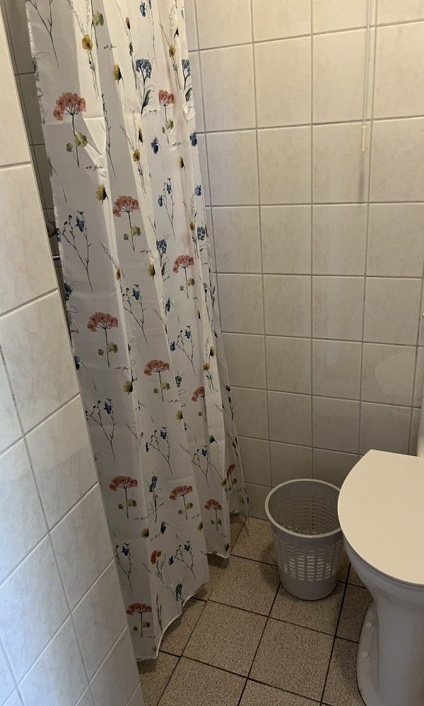Cozy bathroom in Koetshuis vacation home, De Koog, Texel, with a floral shower curtain and light-colored tiles for a fresh look.