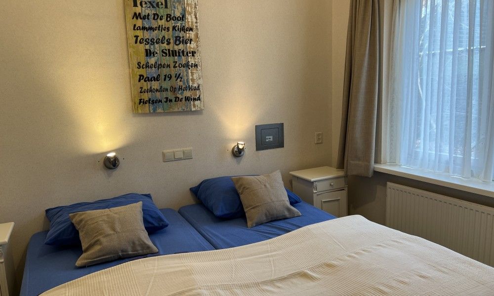 Cozy bedroom in Koetshuis, a vacation home in De Koog, Texel, with a comfortable double bed and atmospheric lighting.