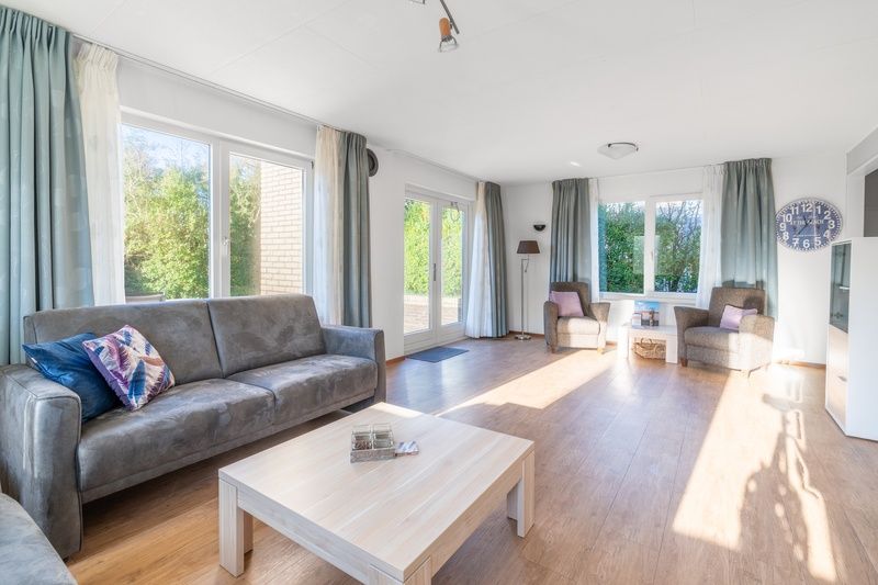 Geraeumiges Wohnzimmer des Ferienhauses Kamperfoelie 97, De Koog, Texel mit Zugang zur Terrasse des Wattenmeeres.