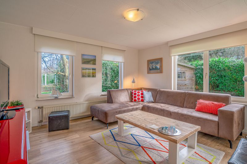 Gemuetliches Wohnzimmer im Ferienhaus Kamperfoelie 29, De Koog, Texel, mit Blick auf den Garten.