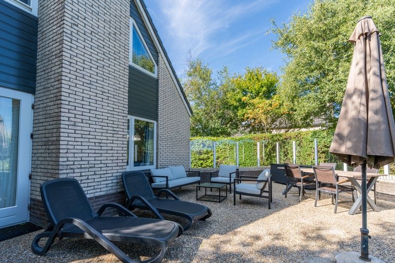 Sunny terrace at Holiday home Kamperfoelie 55 in De Koog Texel with comfortable deck chairs.