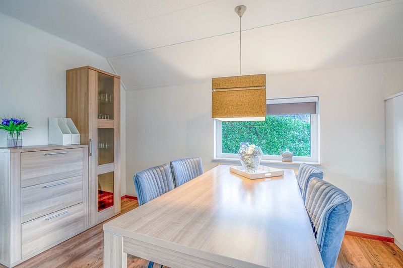 Dining room in Holiday home Honeysuckle 55 De Koog Texel with wooden table and modern lamp.