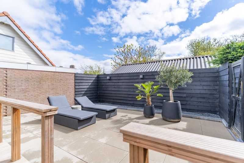 Geraeumige Terrasse mit Liegestuehlen im Appartement Zee van Tijd, De Koog, Texel. Perfekt zum Sonnenbaden und Entspannen.