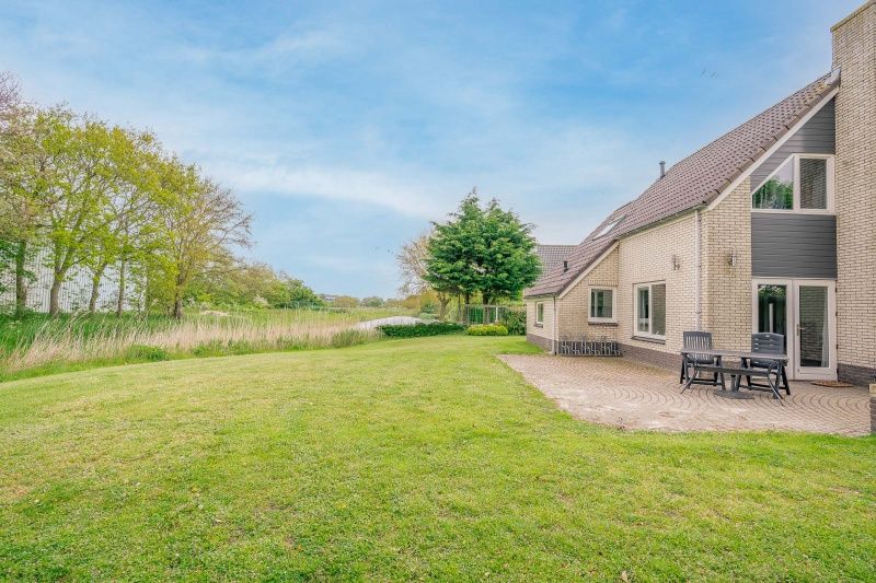 Spacious terrace at Holiday home Honeysuckle 45, De Koog, Texel, overlooking a green garden.