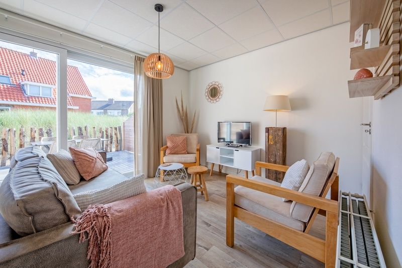 Bright living space in De Duinroos vacation home on Texel overlooking the terrace.