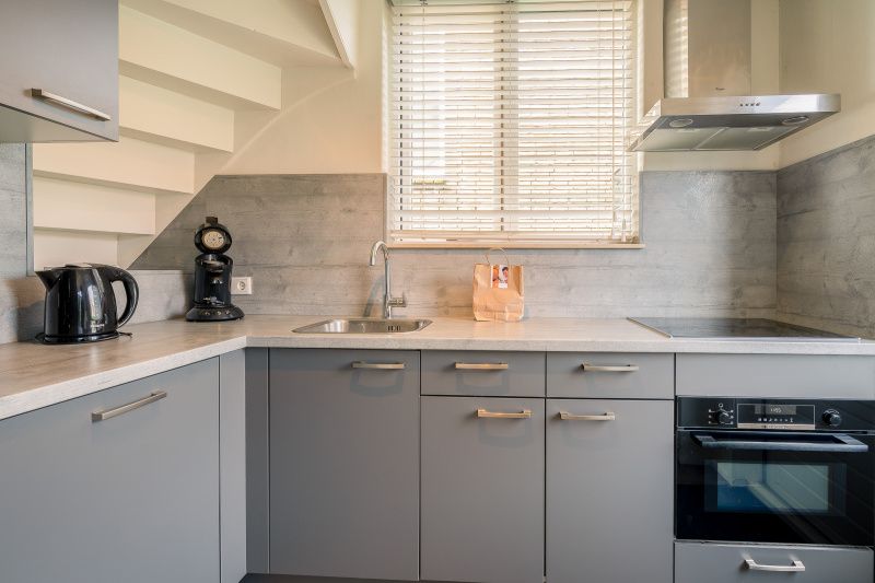 Modern kitchen in De Bosruiter vacation home, De Koog Texel, with sleek gray cabinets and modern appliances.
