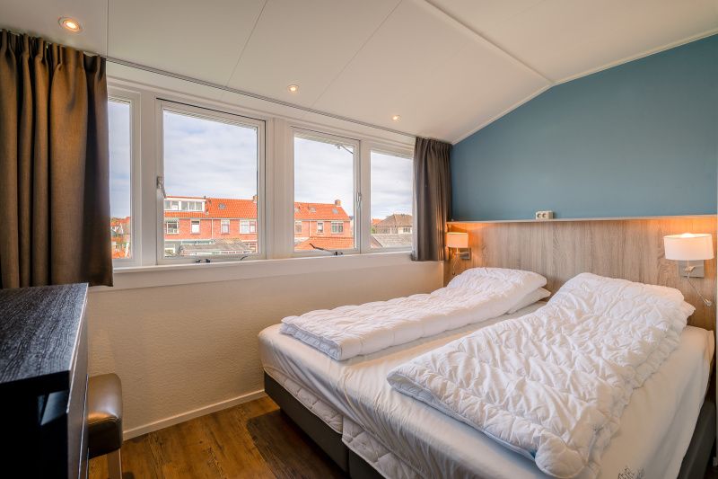 Spacious bedroom in De Bosruiter vacation home, De Koog Texel, with large window and view of the surroundings.