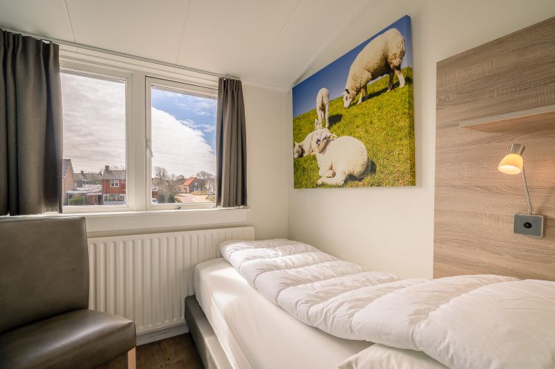 Small bedroom in De Bosruiter vacation home, De Koog Texel, with single bed and sheep painting.