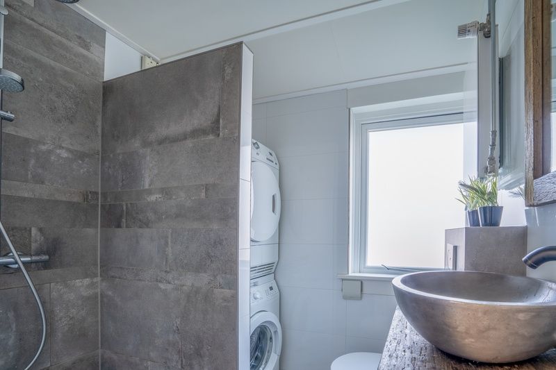 Modern bathroom in De Bosruiter vacation home, De Koog Texel, with shower, washing machine and sink.