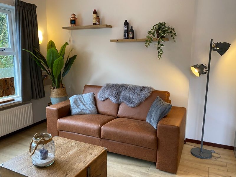 Stilvolles Wohnzimmer des Ferienhauses Jutter in De Koog, Texel. Bequemes Sofa und stimmungsvolle Dekoration.