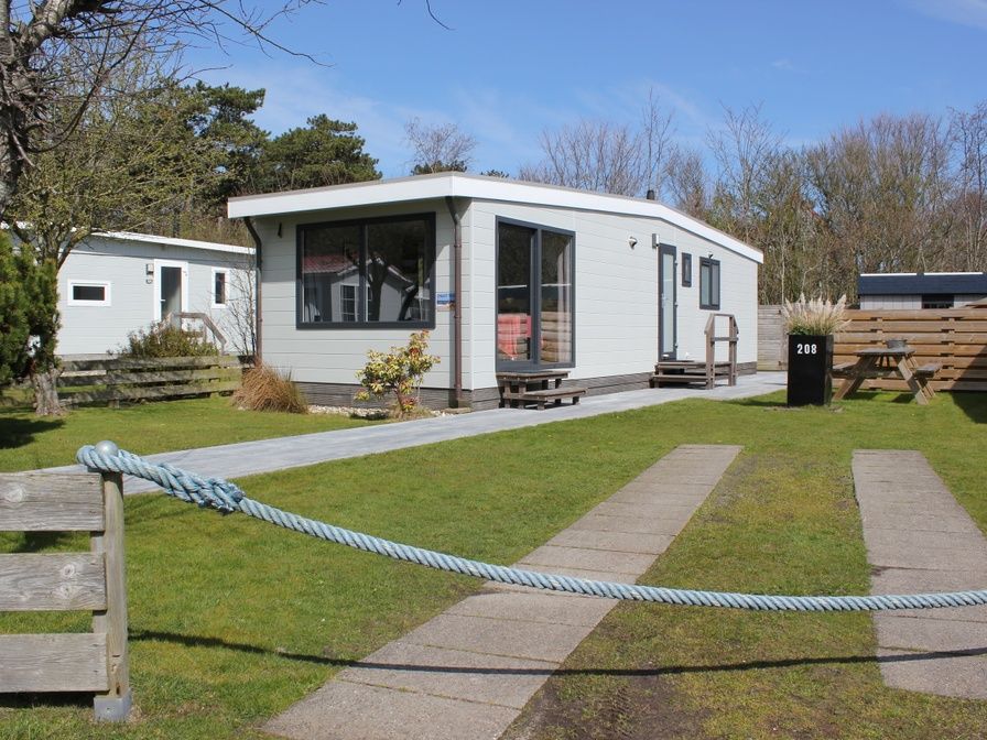 Das Chalet Bregkoog 208 in De Koog, Texel, bietet ein modernes Aeusseres mit grossen Fenstern und einer gruenen Umgebung.
