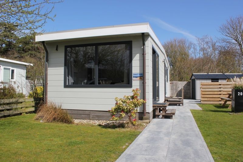 Chalet Bregkoog 208, ein Ferienhaus in De Koog, Texel, mit einer einladenden Veranda und einem Gartensitzplatz.