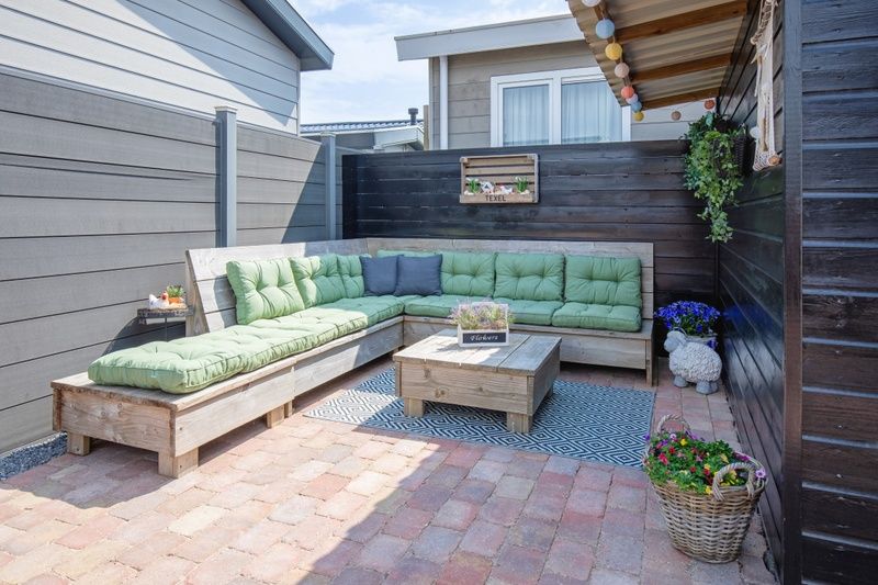 Knusse buitenlounge met groene kussens bij Chalet Bregkoog 88 in De Koog, Texel op Chaletpark Bregkoog.