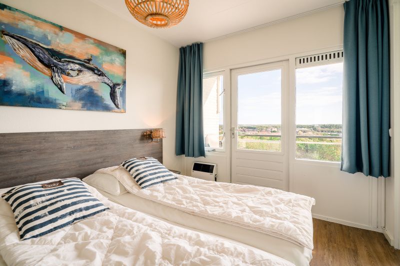 Slaapkamer met uitzicht in Appartement Juliana 176 Eilandzicht, De Koog, Texel, voor een ontspannen verblijf op de Waddeneilanden.