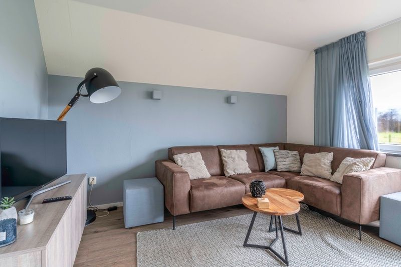 Gemuetliches Wohnzimmer im Nieuwlanderweg 77, De Koog, Texel, mit moderner Einrichtung und Blick auf die Natur des Wattenmeeres.