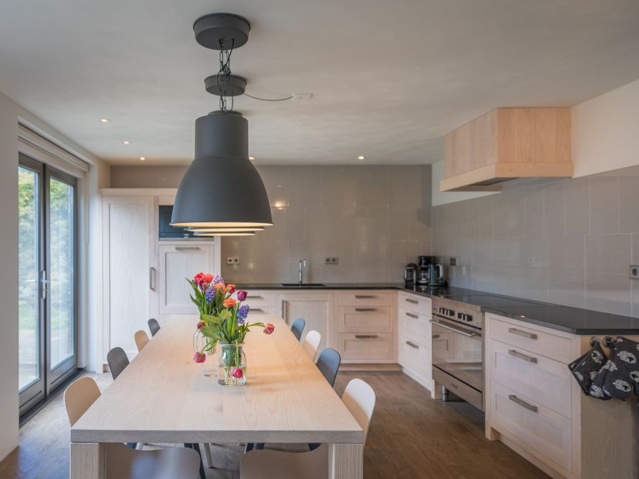 Moderne Kueche im Ferienhaus Orchismient 24, De Koog, Texel, mit grossem Esstisch und stilvoller Beleuchtung.