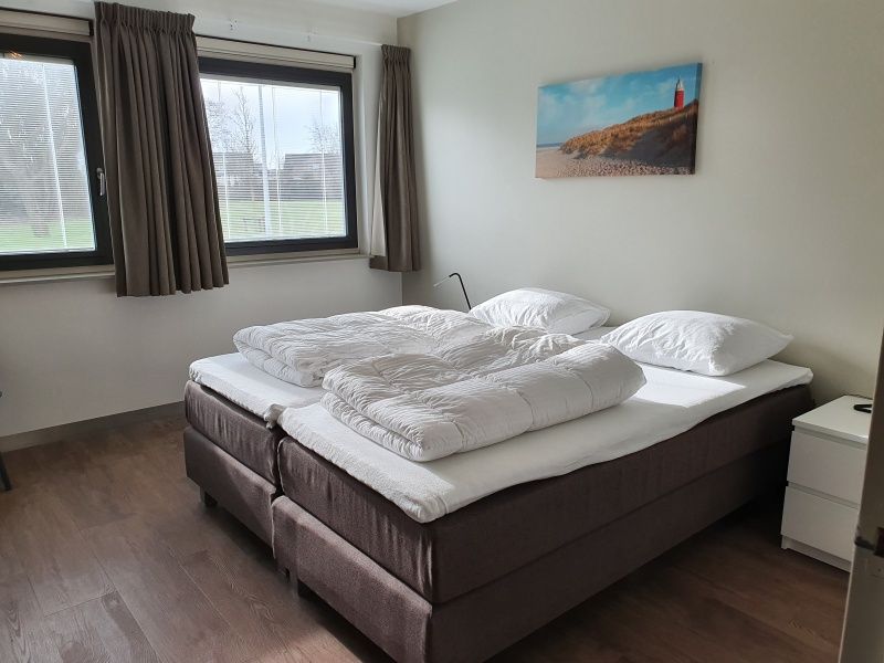 Gemuetliches Schlafzimmer im Ferienhaus Orchismient 24, De Koog, Texel, mit Doppelbett und Kunst an der Wand.