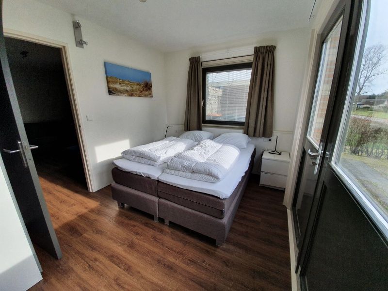 Helles Schlafzimmer in Orchismient 24, De Koog, Texel, mit Zugang zur Terrasse und viel Tageslicht.