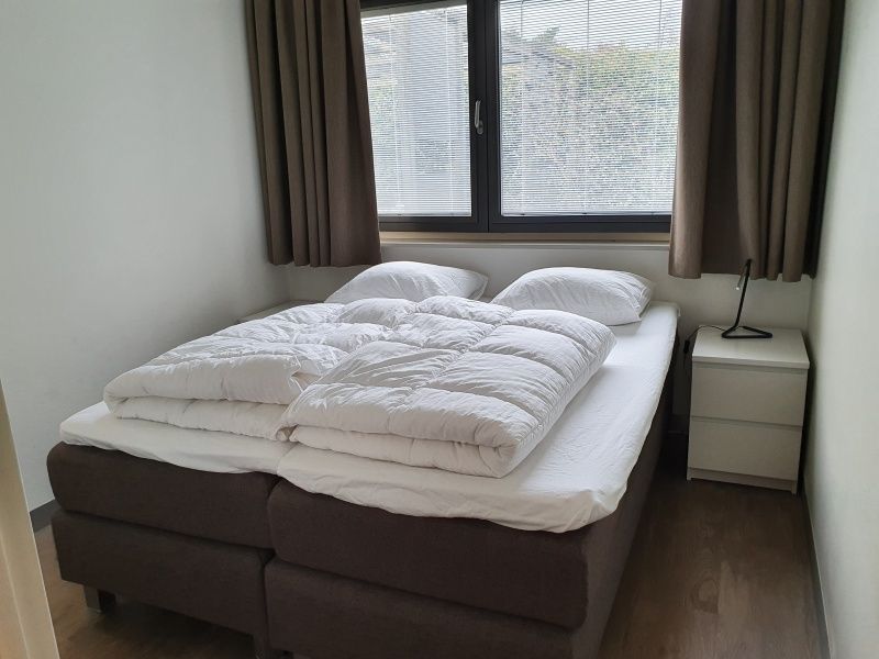 Intimes Schlafzimmer im Ferienhaus Orchismient 24, De Koog, Texel, mit bequemem Bett und Nachttisch.