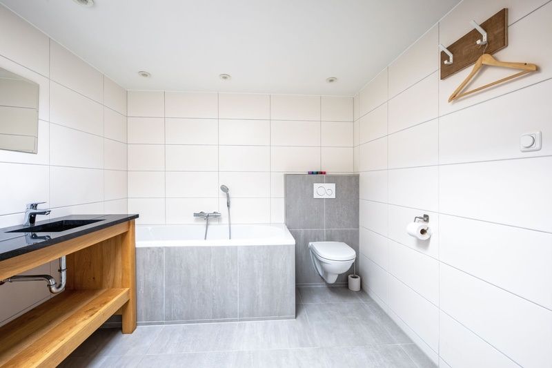 Modern bathroom with bath and toilet in Orchismient 55 vacation home De Koog Texel.