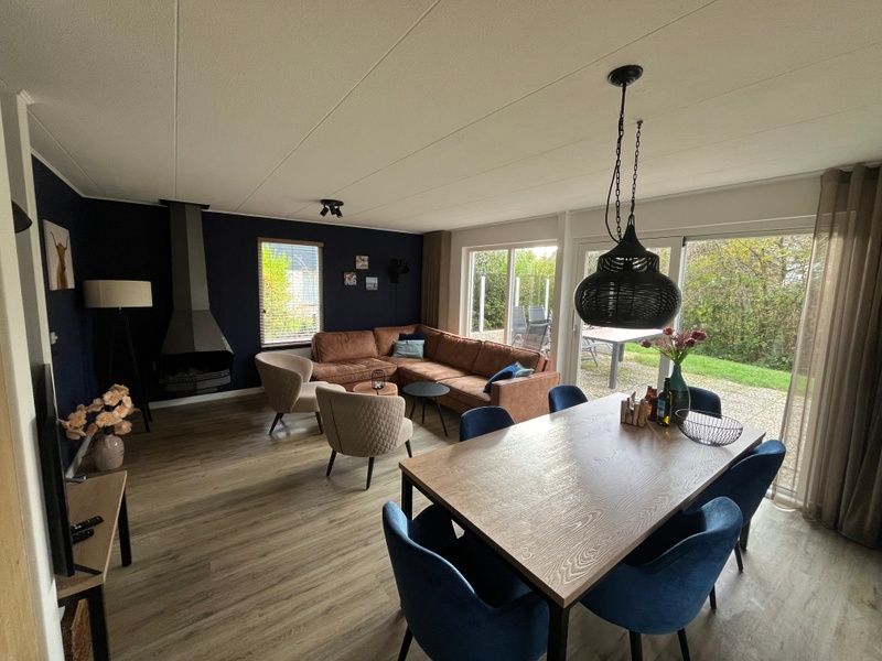 Stijlvolle woonkamer van De Duinven in De Koog, Texel, met uitzicht op de tuin, perfect voor familiebijeenkomsten.