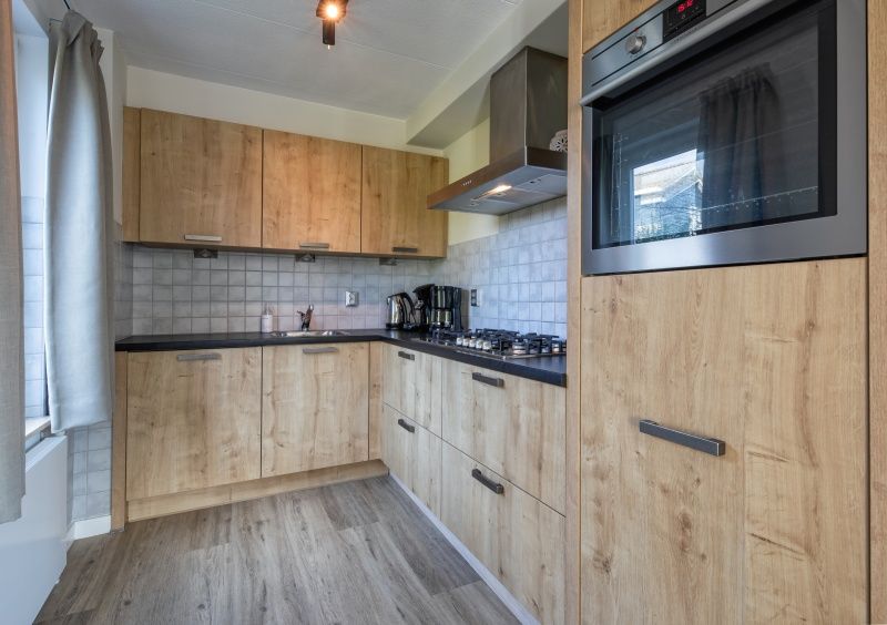 Volledig uitgeruste keuken in De Duinven vakantiehuis, De Koog, Texel, met houten afwerkingen en moderne apparatuur.
