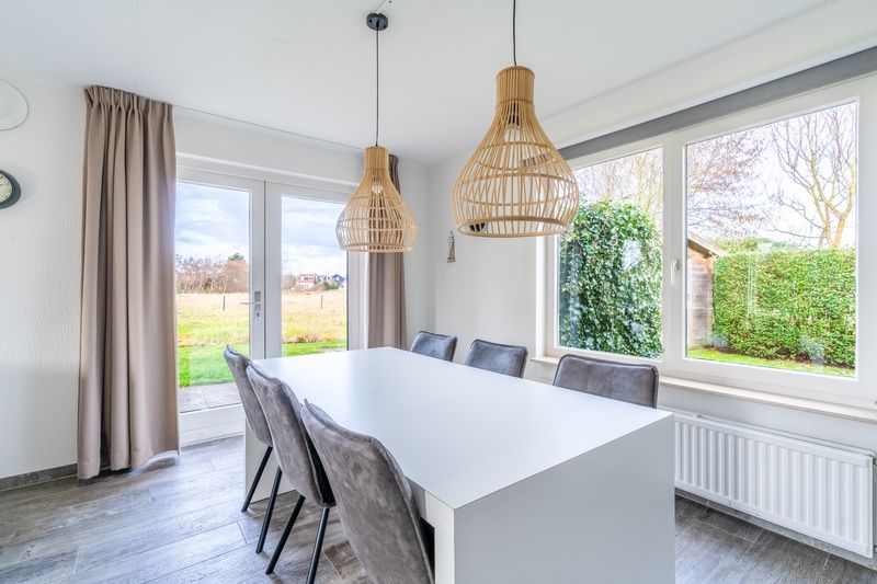 Dining room in Holiday home Honeysuckle 67 De Koog Texel with large table and garden view, perfect for family dinners on the Wadden Islands.